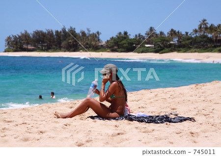 A woman sitting on a sand beach and relaxing A woman sitting on a sand beach and relaxing 745011
