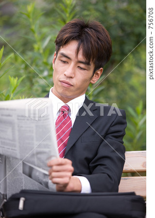 A businessman reading a newspaper on a park bench A businessman reading a newspaper on a park bench 756708
