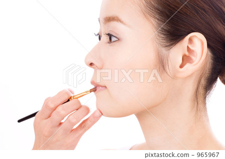 A woman applying lipstick 965967