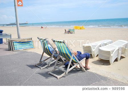 An old couple sunbathering on the South Coast of England 989598