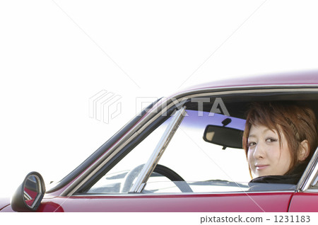 A boyish young lady sending a line of sight from the driver's seat of a red sports car 1231183