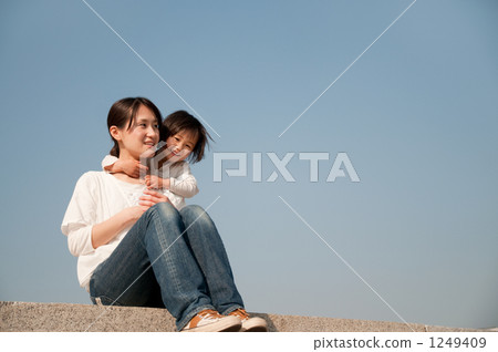 Smiling mother and daughter sitting on the bank Smiling mother and daughter sitting on the bank 1249409