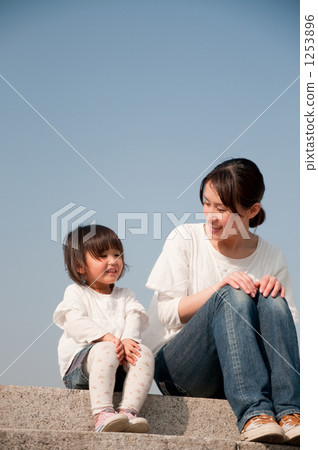 Smiling mother and daughter sitting on the bank Smiling mother and daughter sitting on the bank 1253896