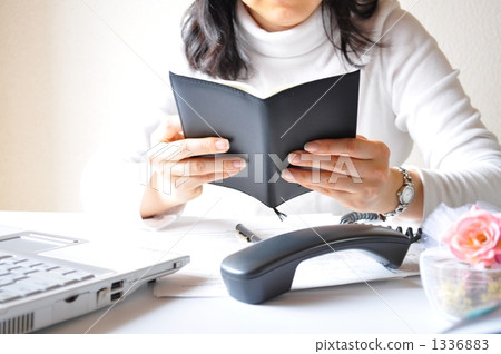 A business woman that puts the receiver and checks the schedule A business woman that puts the receiver and checks the schedule 1336883