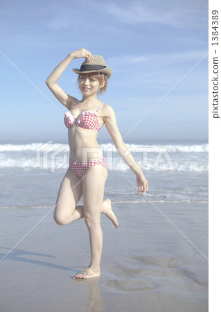 游泳衣的一名婦女在沙子 游泳衣的一名婦女在沙子 1384389