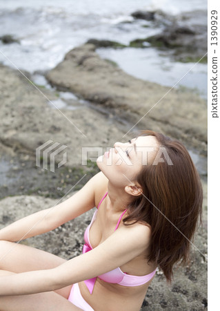 游泳衣的一名婦女坐一個岩石地方 1390929
