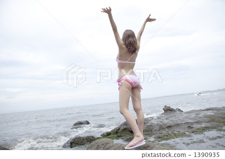A woman in a bathing suit on a rocky side 1390935
