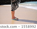 A woman standing on a sandy beach and looking at the sea A woman standing on a sandy beach and looking at the sea 1558992