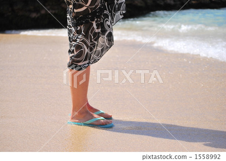 A woman standing on a sandy beach and looking at the sea A woman standing on a sandy beach and looking at the sea 1558992