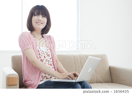 A young woman operating a computer with a sofa 1656435