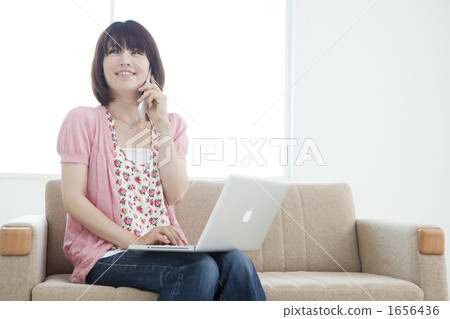 A young lady who calls while operating a computer with a sofa 1656436