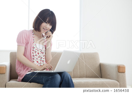 A young lady who calls while operating a computer with a sofa 1656438