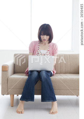 A young woman operating a computer with a sofa 1656485