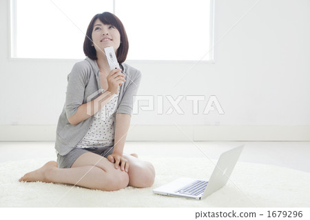 A woman carrying a cell phone in front of a personal computer A woman carrying a cell phone in front of a personal computer 1679296