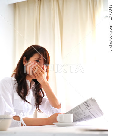 A woman reading a newspaper while eating breakfast A woman reading a newspaper while eating breakfast 1773348
