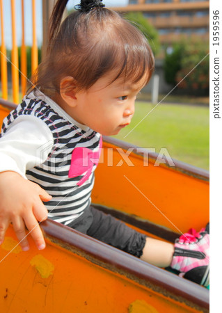 A 1 year old girl playing on a slide 1959596