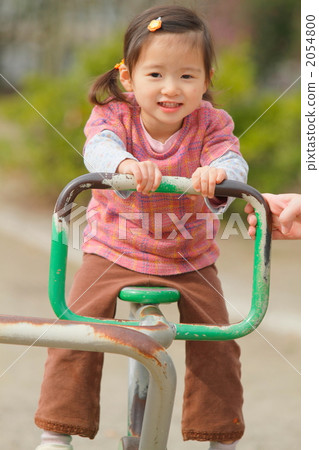 騎操場的一個兩歲的女孩在公園 騎操場的一個兩歲的女孩在公園 2054800