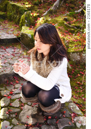 A woman who wears a leaf hill (picks up a maple with a squat down) 2168178