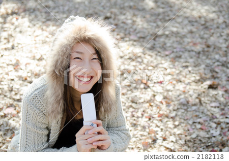 A woman carrying a cell phone in a park in winter A woman carrying a cell phone in a park in winter 2182118
