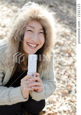 A woman carrying a cell phone in a park in winter A woman carrying a cell phone in a park in winter 2182125