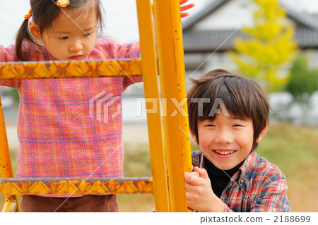 A 2 year old girl who climbs the stairs on the slide and a big brother with a smile 2188699