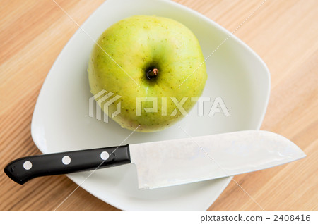 A plate with a green apple and a knife on it. A plate with a green apple and a knife on it. 2408416