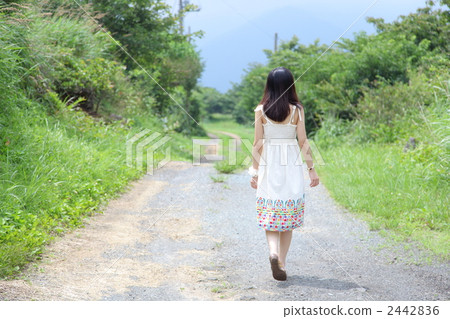 A woman walking along a country road A woman walking along a country road 2442836