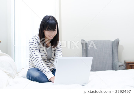 在房間裡享受個人電腦的女人 在房間裡享受個人電腦的女人 2592497