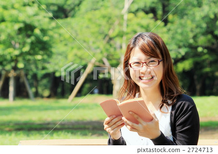 A smiling woman reading in the park 2724713