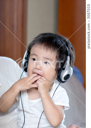 One-year-old boy looking at the computer with headphones One-year-old boy looking at the computer with headphones 3087010