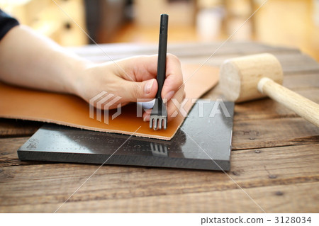 A woman's hands punching holes in leather craft 3128034