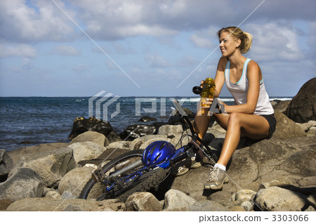 Attractive Young Woman Sitting With Bicycle on Rocky Beach 3303066