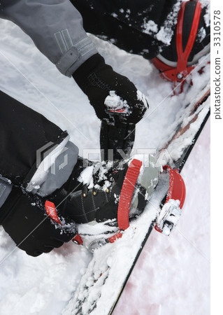 Person strapping on snowboard. 3310578