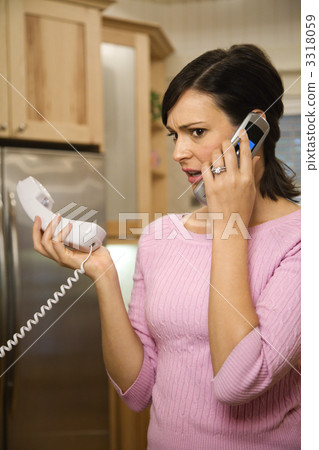 Serious woman on two telephones. Serious woman on two telephones. 3318059
