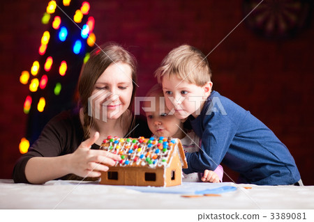 Mother with kids making gingerbread house 3389081