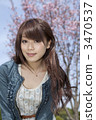 A woman looking at the front of a cherry tree 3470537