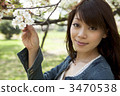 A woman looking at a cherry tree in her hand 3470538