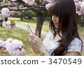 A woman taking cherry blossoms on a smartphone 3470549