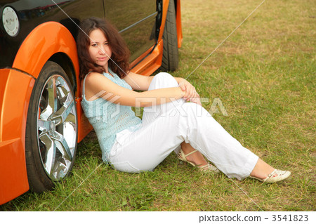Girl sits on grass near car 3541823