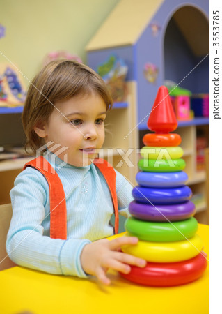 Little girl plays in kindergarten with plastic pyramid 3553785