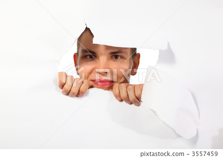 young man looking out in hole in paper 3557459