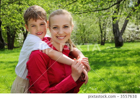 son embraces behind mother in park in spring son embraces behind mother in park in spring 3557638