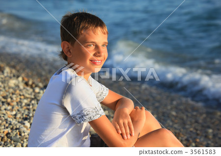 sitting teenager boy on stone seacoast 3561583