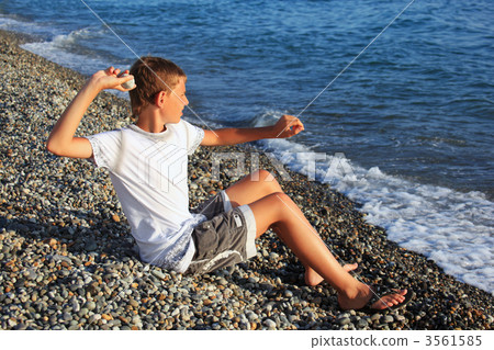 sitting boy throws stone in sea 3561585