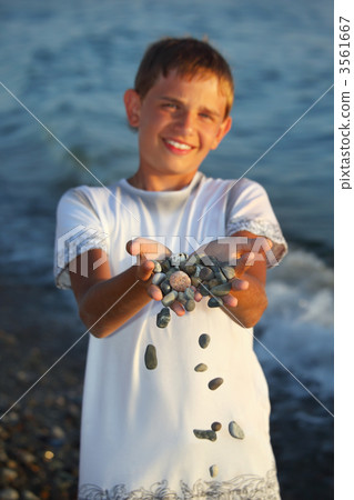 teenager boy with handful of stones in hands, scatter stones 3561667