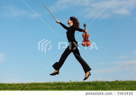 girl with violin jumps on grass against sky girl with violin jumps on grass against sky 3563430
