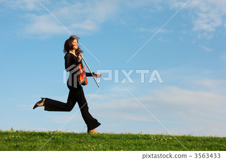 girl with violin runs on grass against sky, side view girl with violin runs on grass against sky, side view 3563433