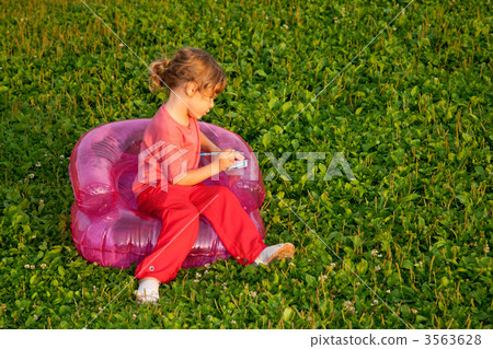 young writing girl sits in inflatable armchair young writing girl sits in inflatable armchair 3563628