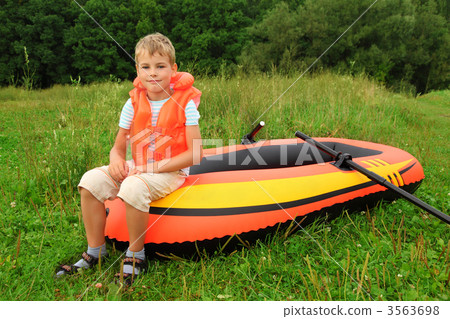 boy sits on an inflatable boat on lawn boy sits on an inflatable boat on lawn 3563698