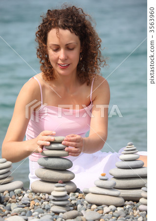 young woman builds  stone stacks on pebble beach 3563960